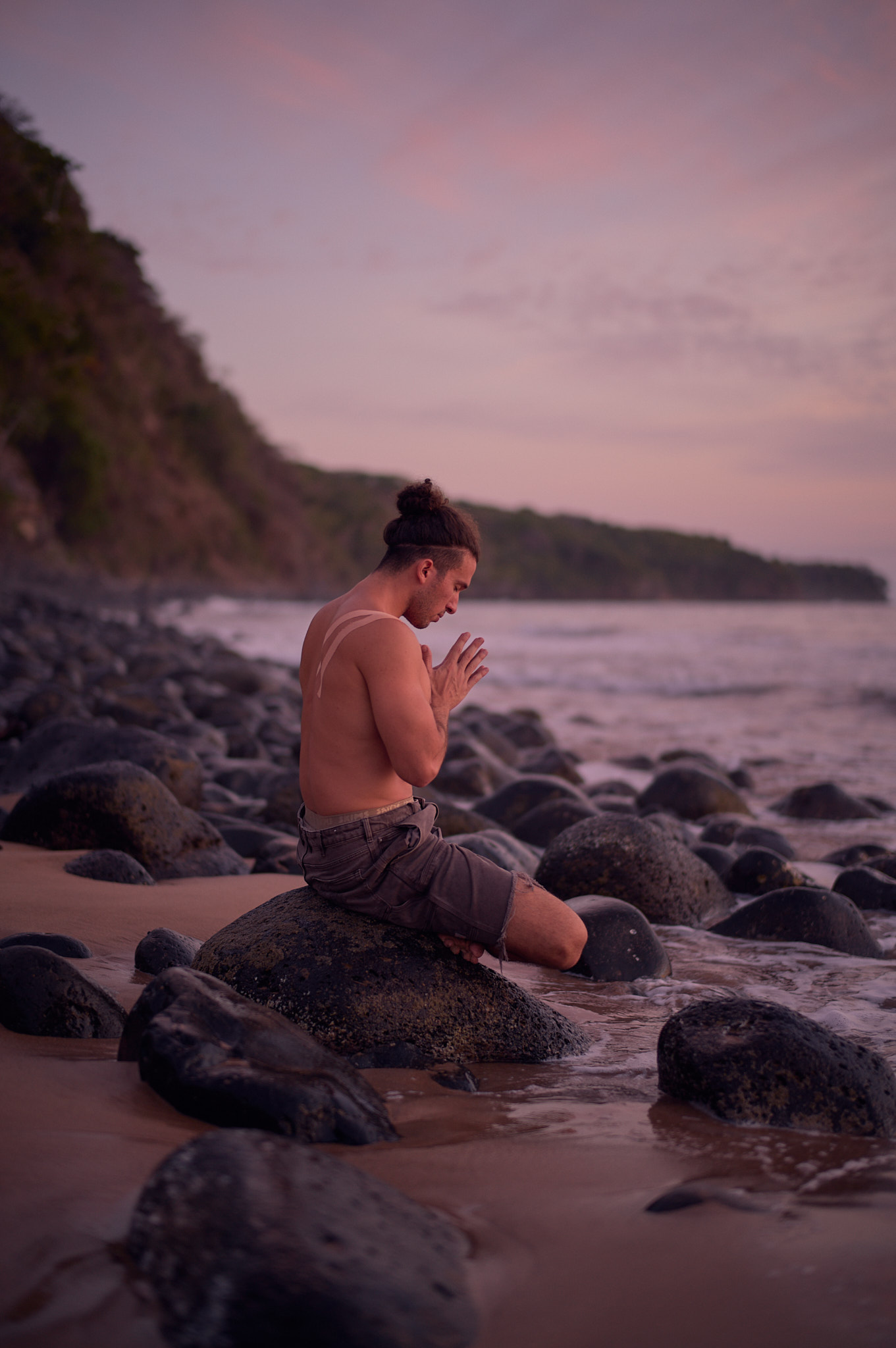 Jonah Kest seated on a tide-worn boulder in anjali mudra at first light, the lineage carried into stillness.