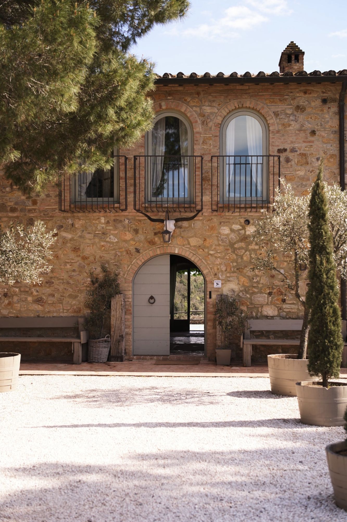 A stone farmhouse among cypress at golden hour in the Tuscan countryside.