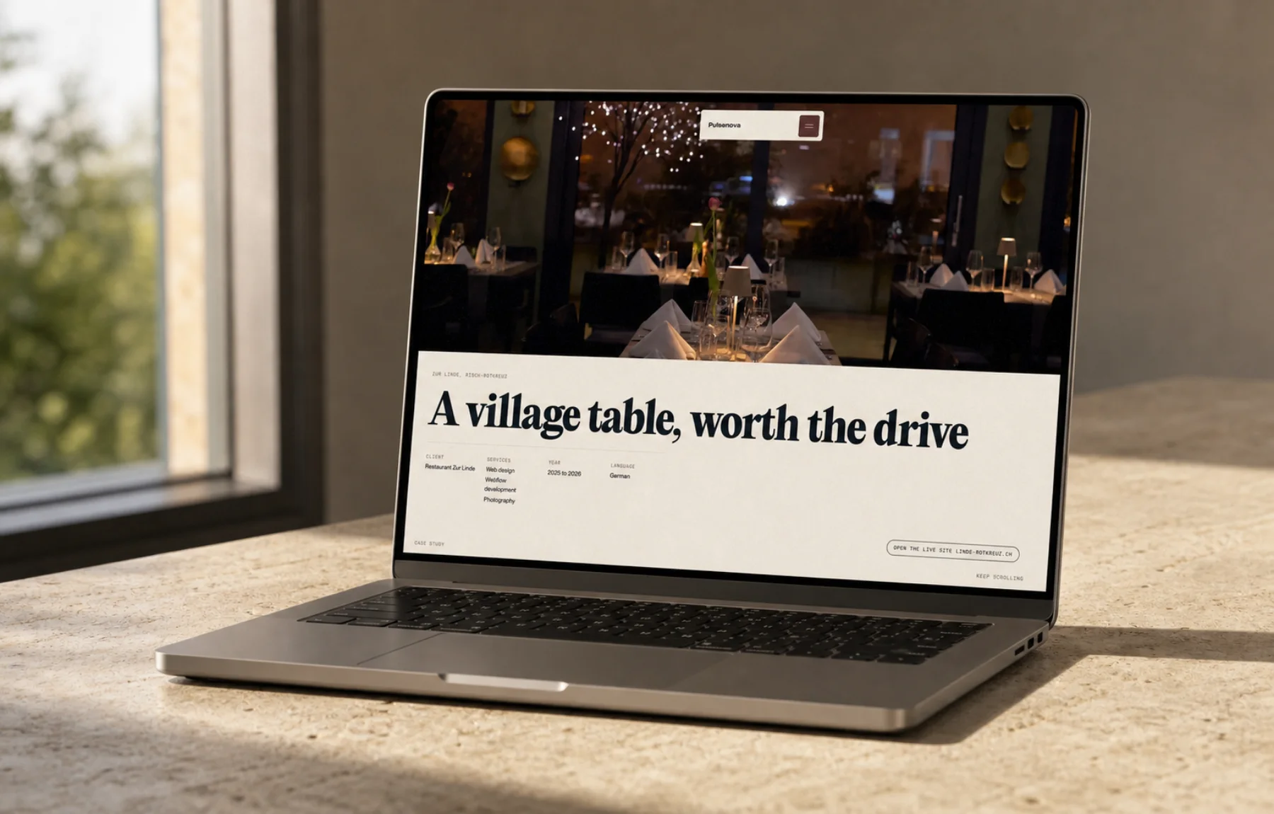 A laptop by a window showing the Zur Linde site, headline A village table, worth the drive